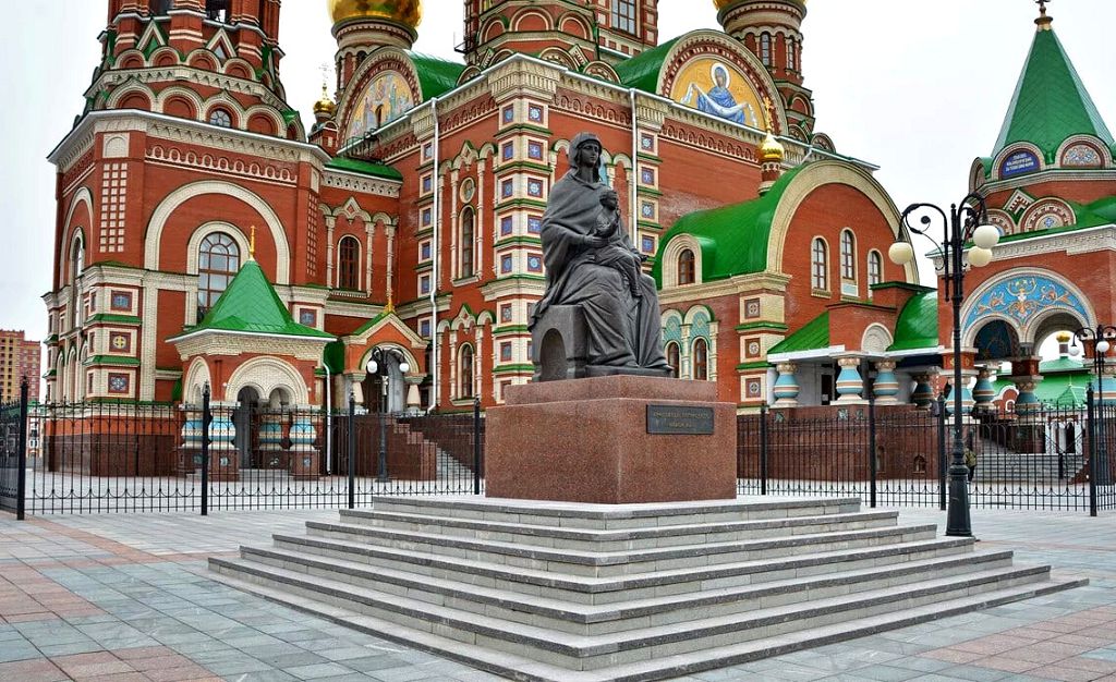 Памятник Деве Марии находится слева от входа в храм